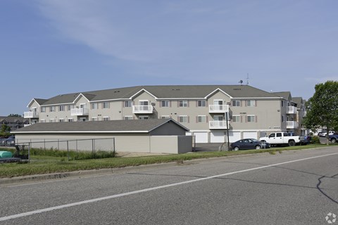 Apartment complex with a parking lot in front.