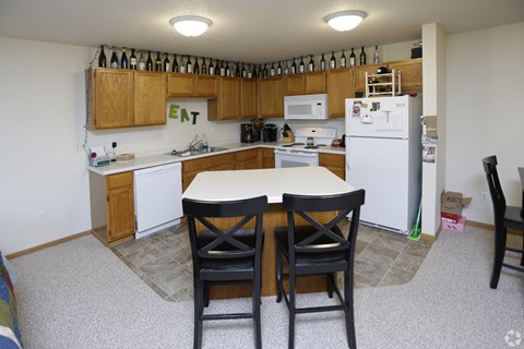 A kitchen with a table and chairs in front of it.