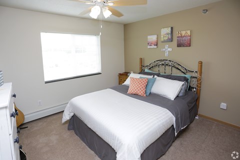 A bedroom with a bed, a ceiling fan, and a guitar.