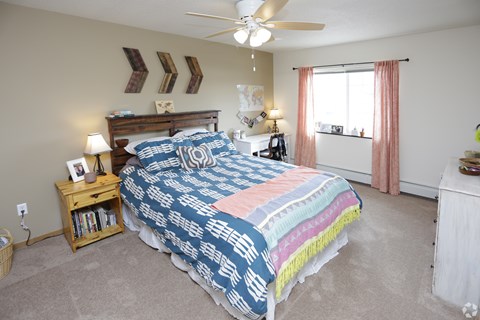 A bedroom with a bed, nightstand, and window.