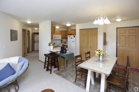A kitchen with a table and chairs in the foreground and a couch in the background.