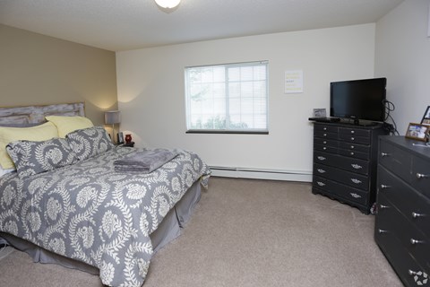 A bedroom with a bed, dresser, and television.