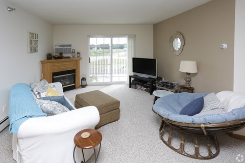 A living room with a white couch, a wooden fireplace, a television, and a rocking chair.