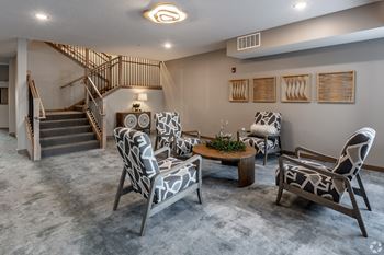 A living room with a grey carpet and a wooden staircase.
