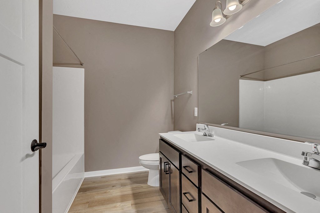 A bathroom with a white sink, a white toilet, and a white door.