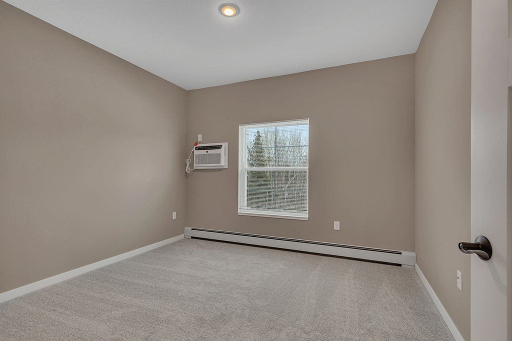 A room with a window and a carpeted floor.