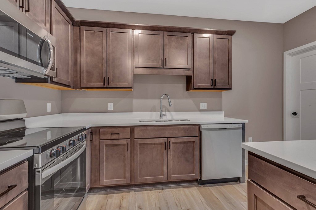 A kitchen with brown cabinets and a white dishwasher.