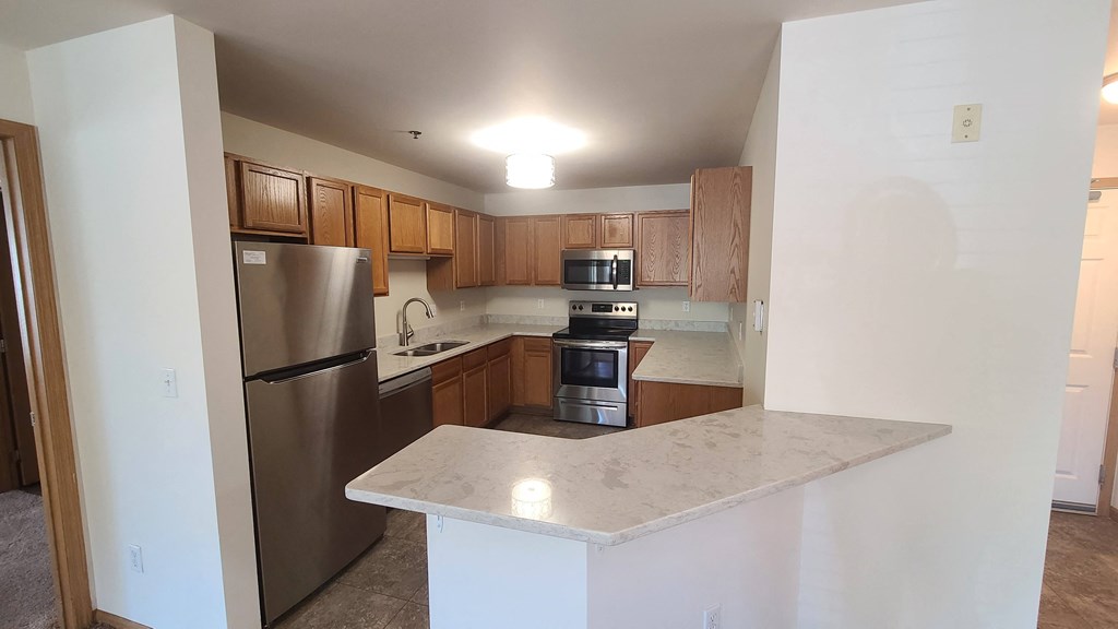 an empty kitchen with stainless steel appliances and a marble counter top