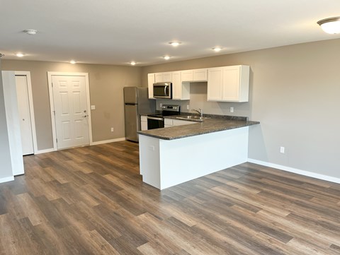 A kitchen with a white countertop and wooden flooring.