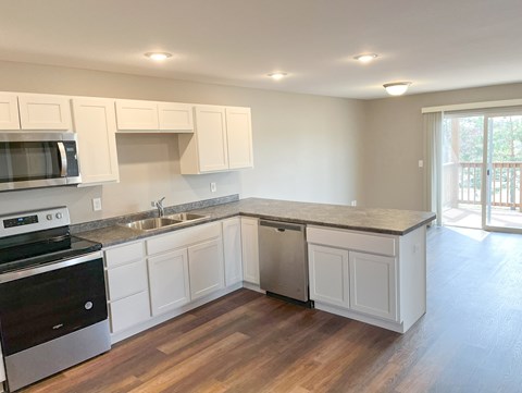 A kitchen with white cabinets and a wooden floor.