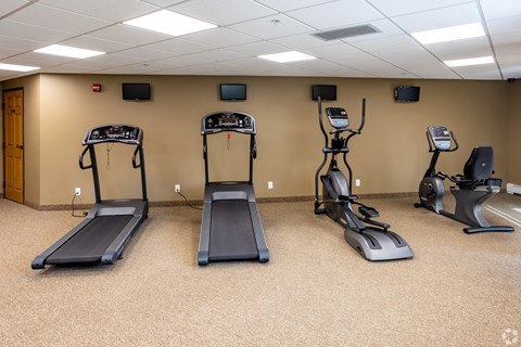 a gym with four treadmills in a room
