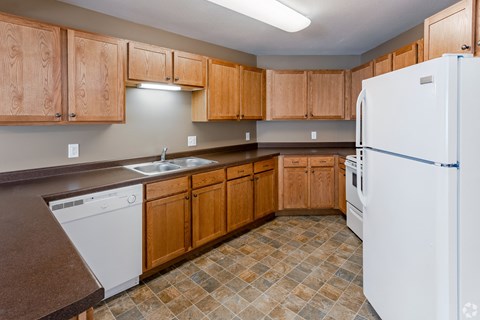 an empty kitchen with white appliances and wooden cabinets