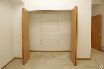 a walk in closet with a wooden door and white walls