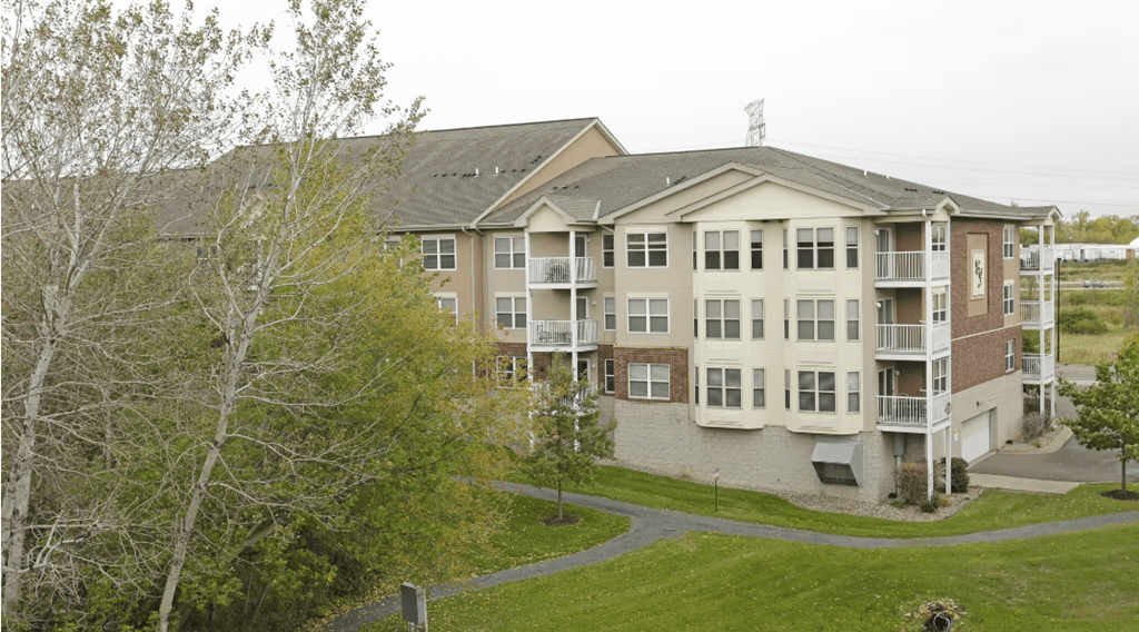 a large apartment building with balconies and a grassy area in front of it