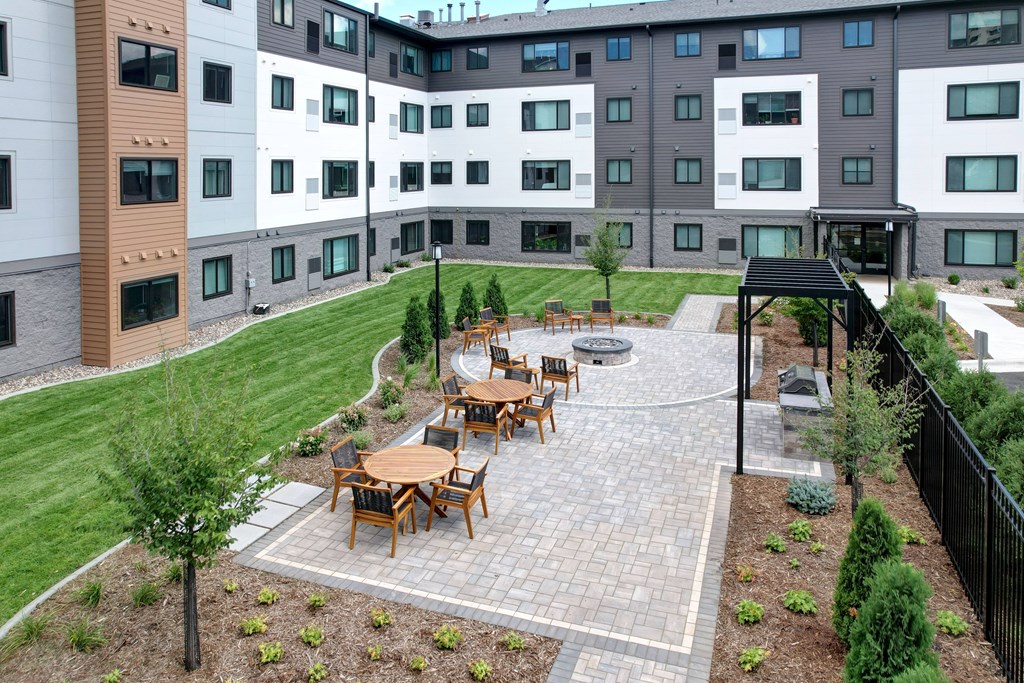 A patio with a table and chairs is surrounded by a black fence.