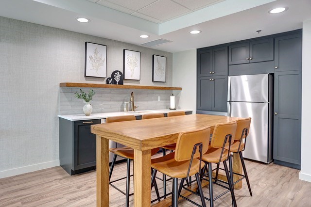 A kitchen with a table and chairs in front of a refrigerator.