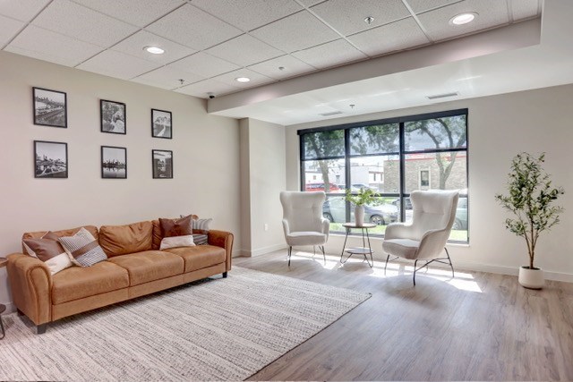 A living room with a brown couch, two chairs, and a plant.