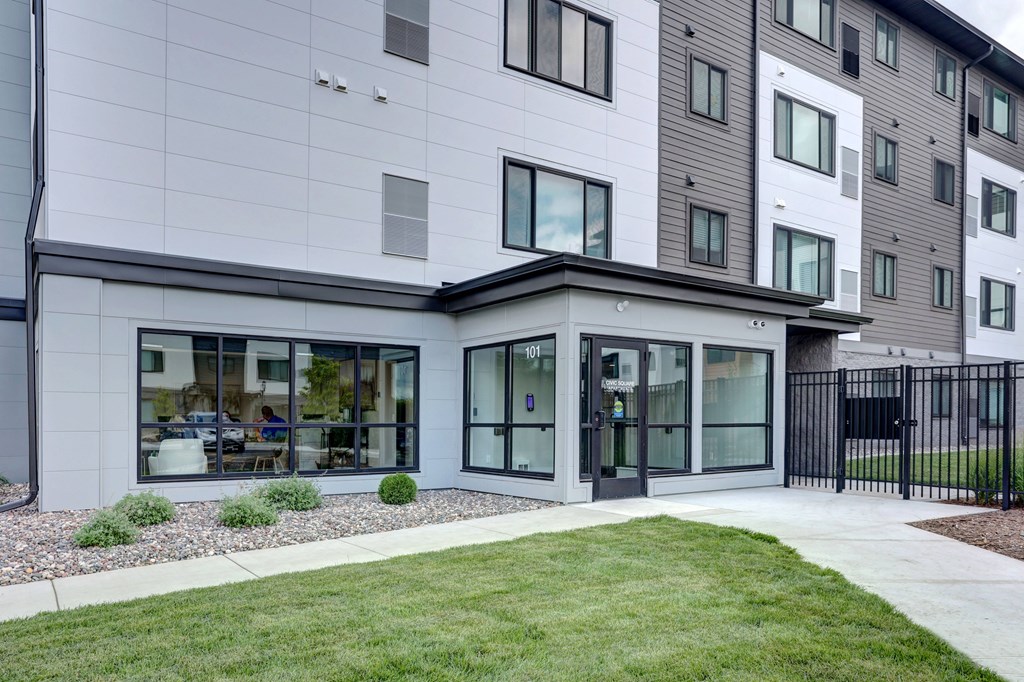 A modern building with a white and grey exterior and a black fence.