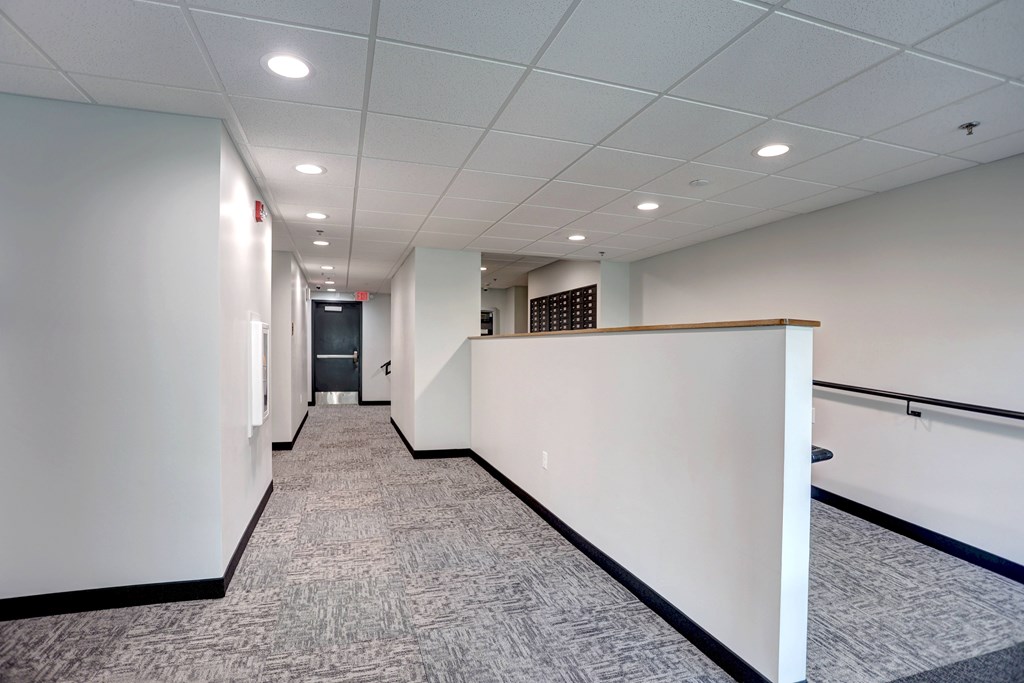 A long hallway with carpeted floors and white walls.