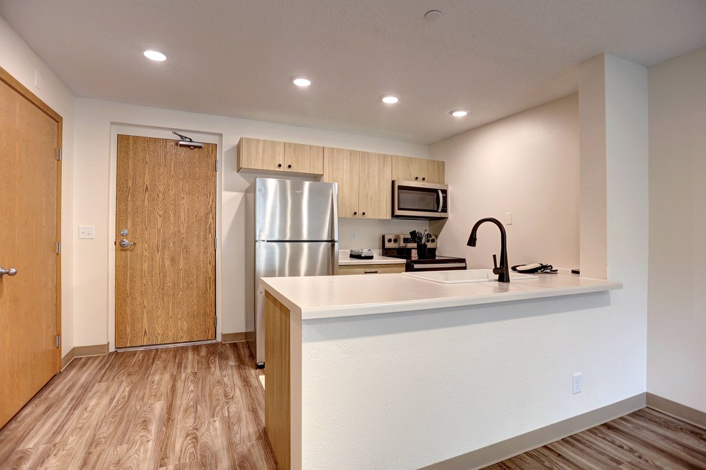 A kitchen with a refrigerator, microwave, and sink.