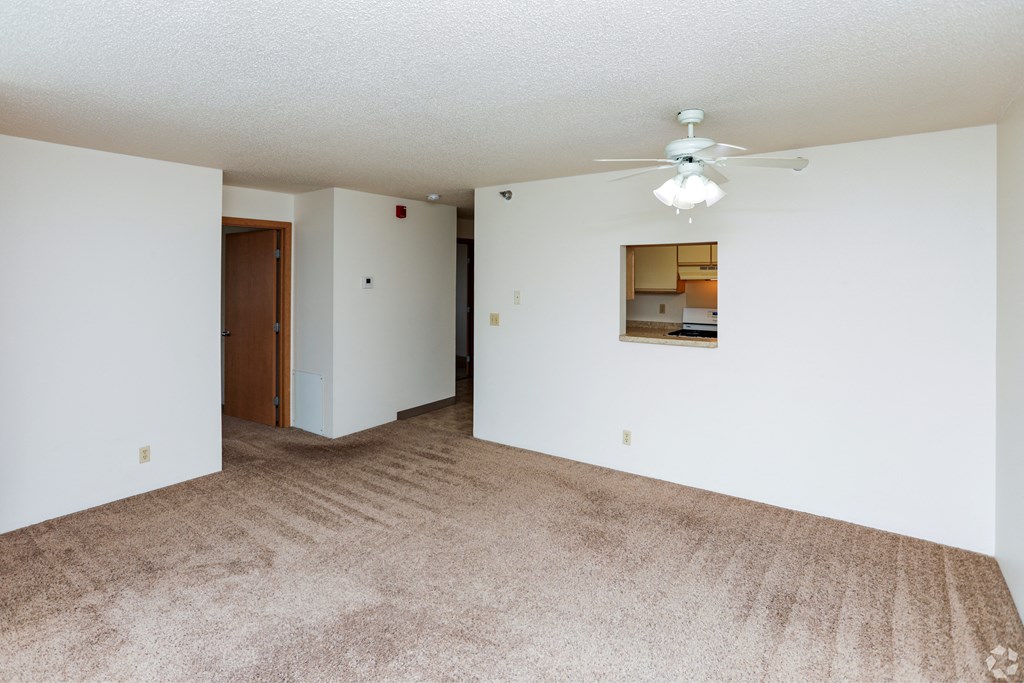 A room with a carpeted floor and a ceiling fan.