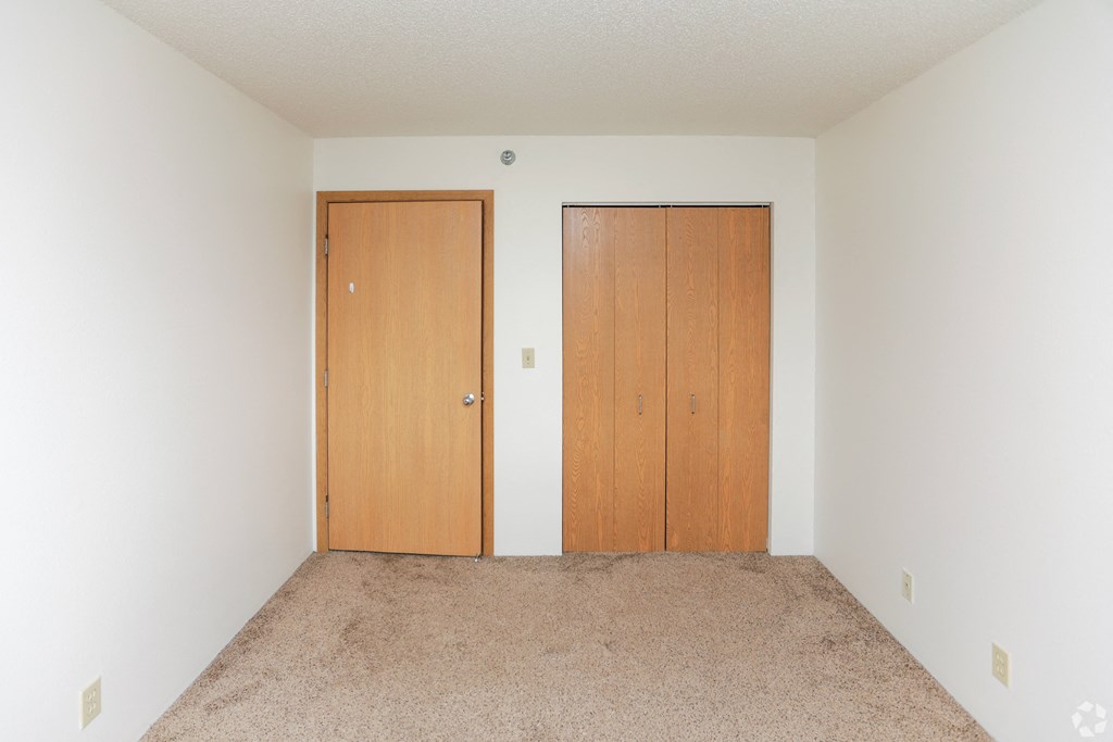 A room with two doors and carpeted floor.