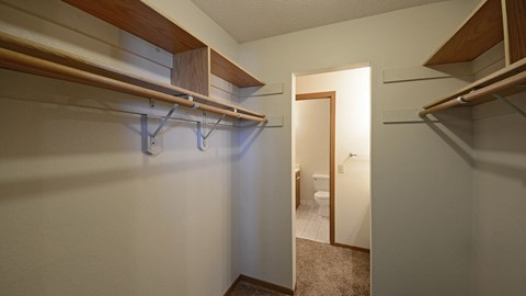 A hallway with a white wall and a doorway leading to a bathroom.