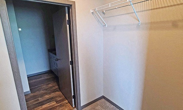 a walk in closet with a white wall and a sliding door