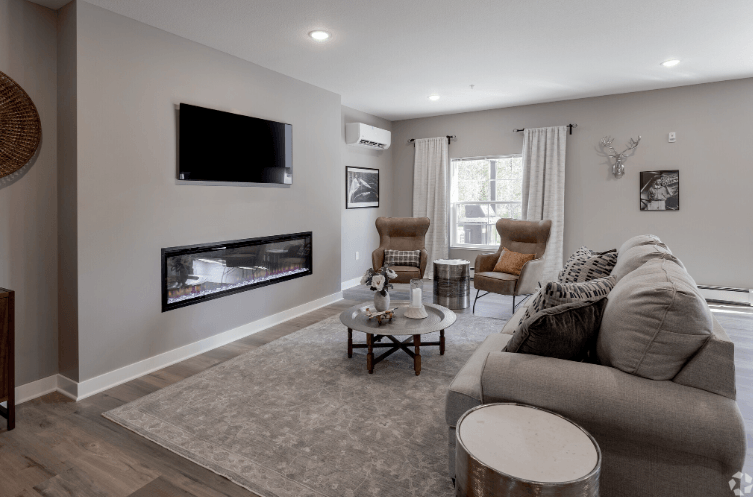 A living room with a grey couch and a television on the wall.