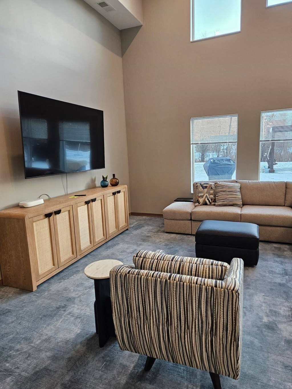 A living room with a striped chair and a couch.