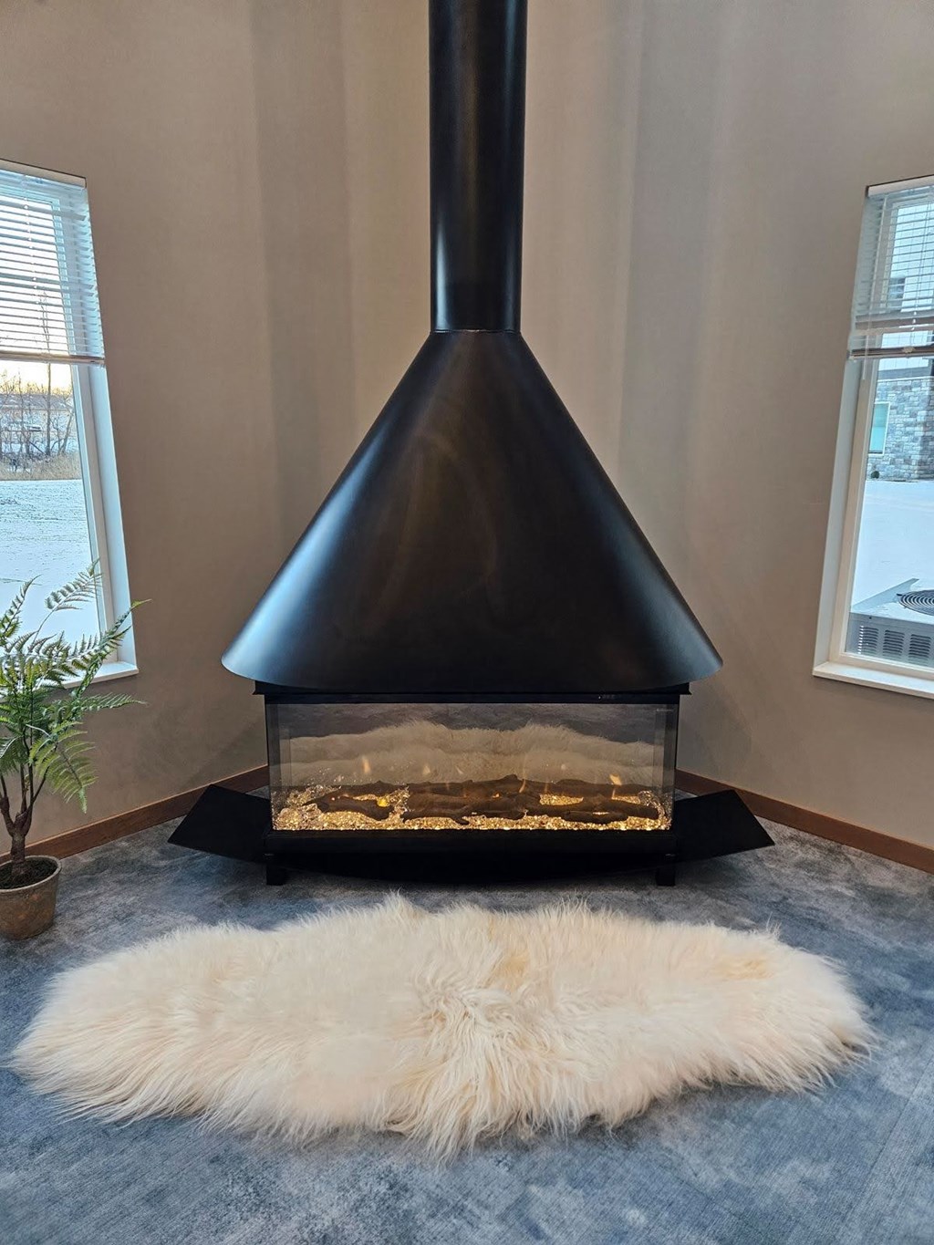 A black wood stove in a room with a white furry rug in front of it.