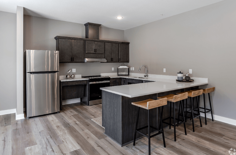 A modern kitchen with a stainless steel refrigerator and wooden flooring.