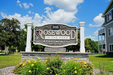 A sign for Rosewood Apartments is displayed in front of a building.
