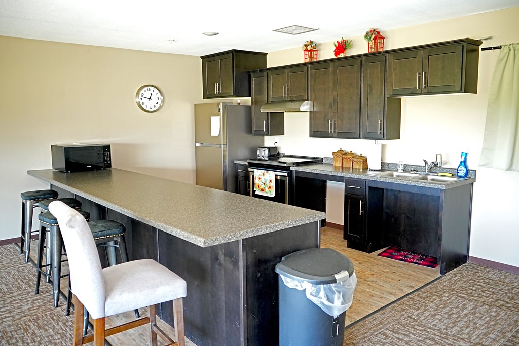 A kitchen with a bar area and a clock on the wall.