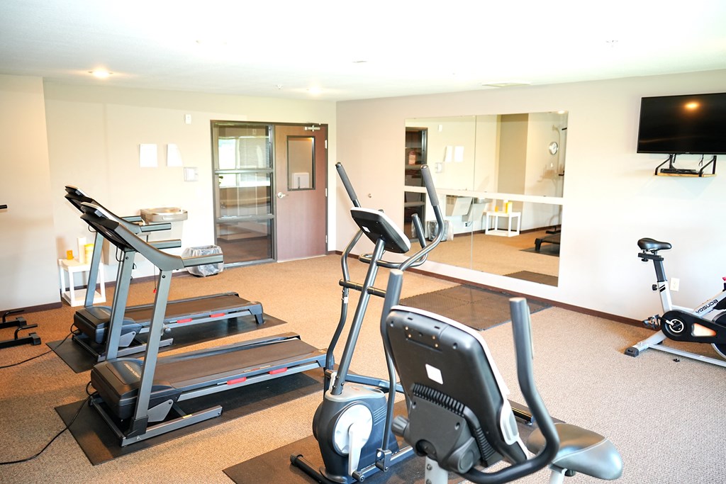 A home gym with a treadmill, elliptical trainer and a stationary bike.