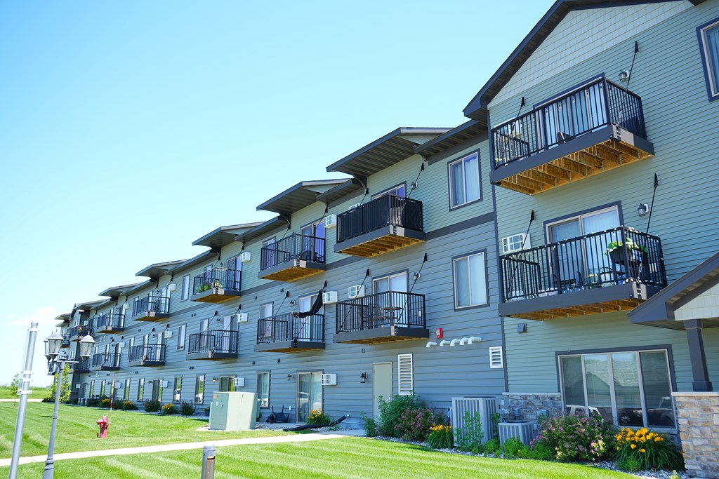 Apartment building with balconies and flower pots in front.