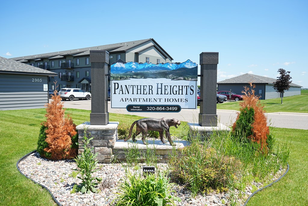 A sign for Panther Heights Apartment Homes is in front of a building.