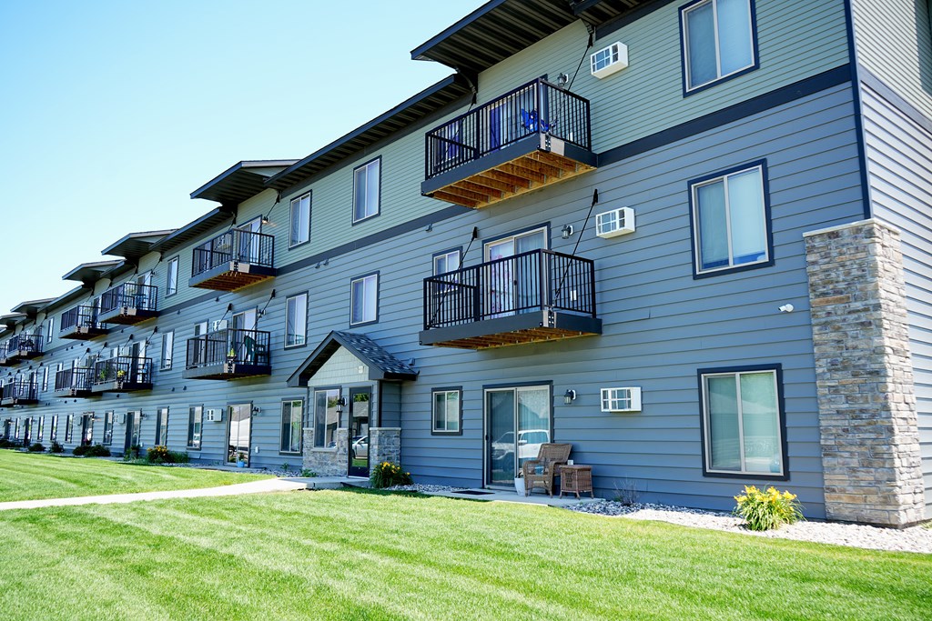 Apartment building with balconies and green lawn in front.