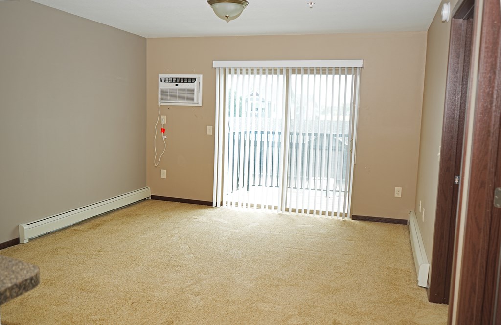 A room with a carpeted floor, a window with blinds, and a ceiling fan.