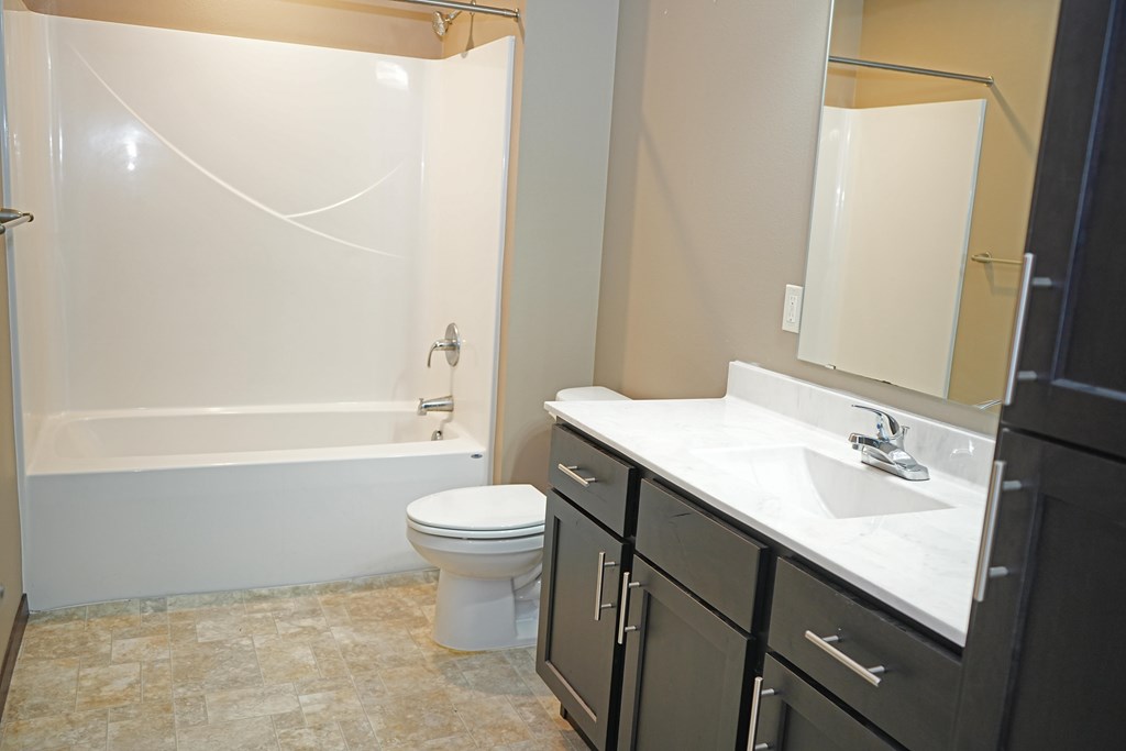 A white toilet sits in a bathroom next to a sink.