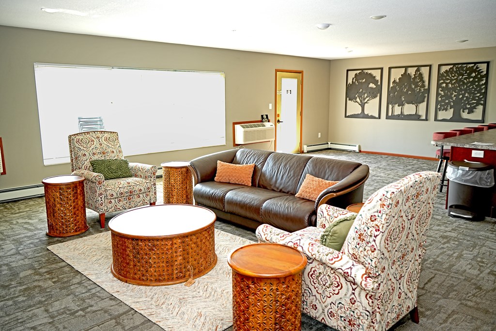 A living room with a couch, chairs, and ottomans.
