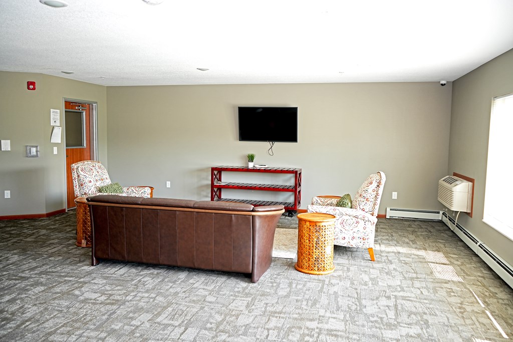 A living room with a brown couch, a chair, and a television.