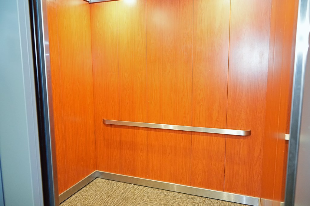 A hallway with orange walls and a metal rail.