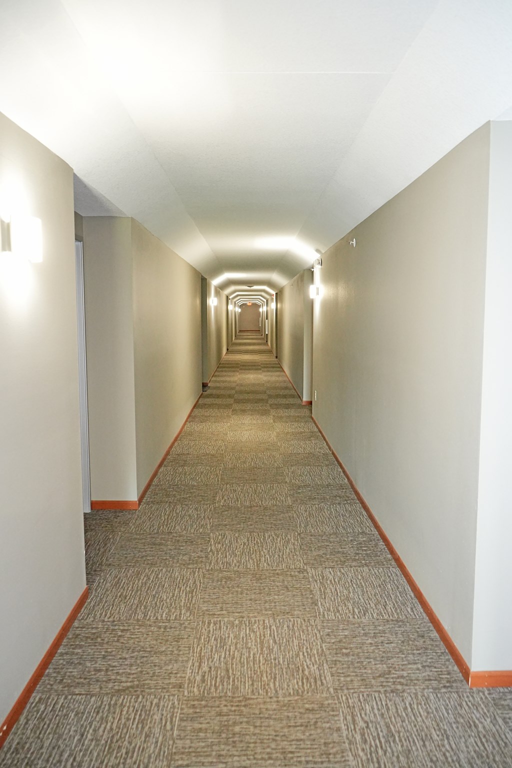 A long hallway with carpeted floors and white walls.