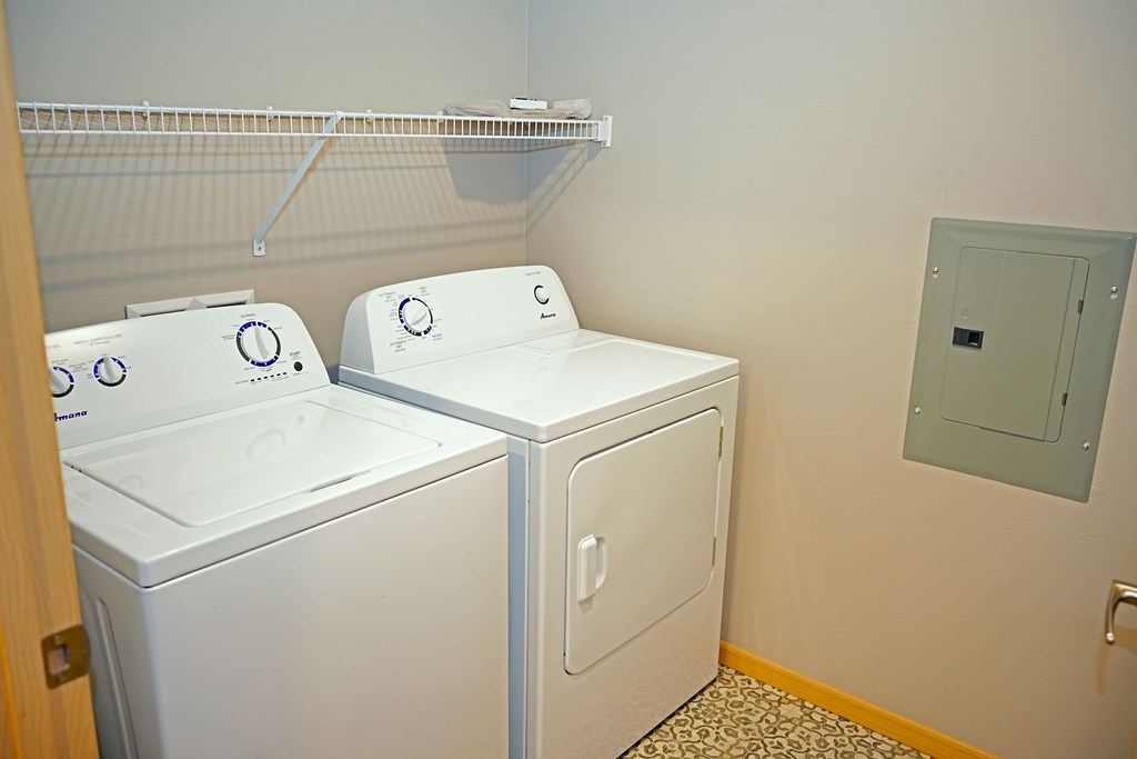 Two white front loading washing machines in a laundry room.