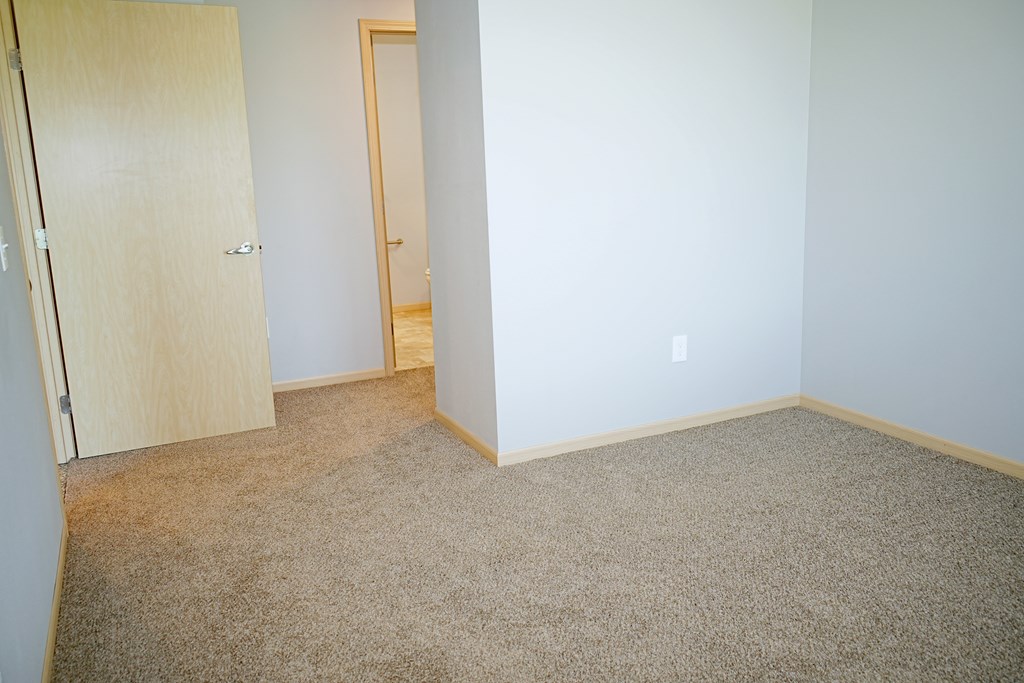 A room with a carpeted floor and a door on the left.
