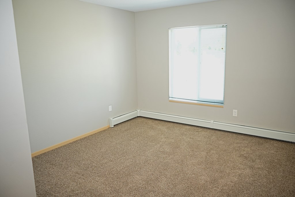 A room with a carpeted floor and a window.