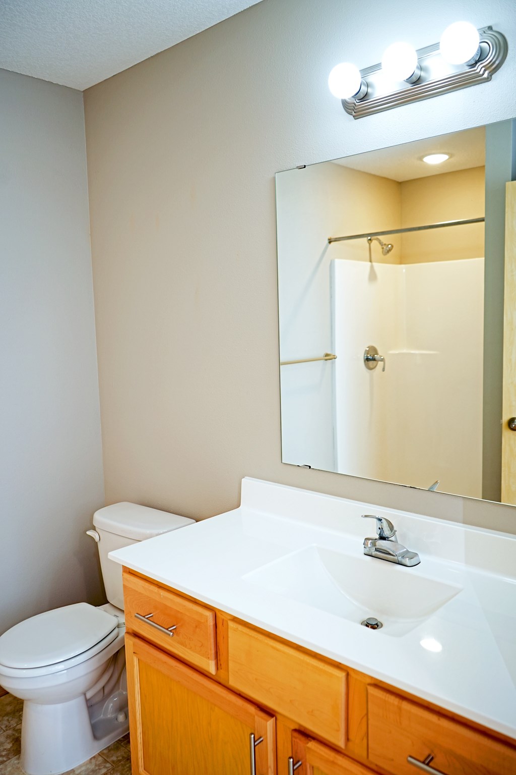 A white toilet sits under a mirror in a bathroom.