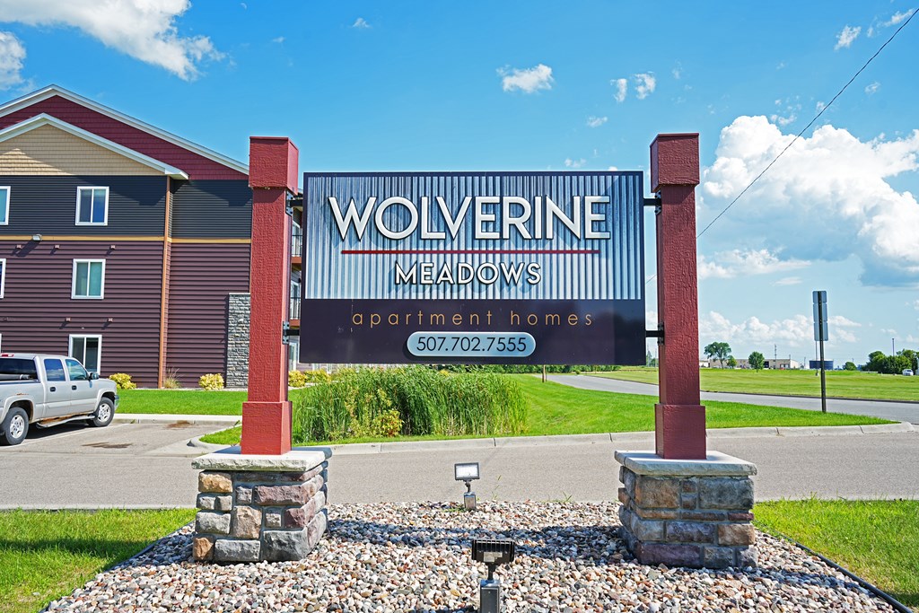 A sign for Wolverine Meadows Apartment Homes stands in front of a building.