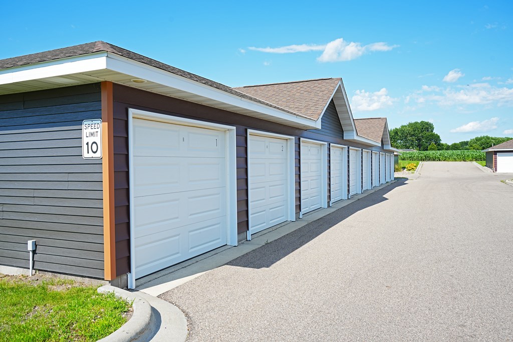 A long row of garage doors are closed and the sign says speed limit 10.